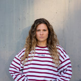 Woman wearing a red and white striped sweater against a concrete wall