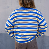 Person wearing a blue and white striped shirt against a gray concrete wall.