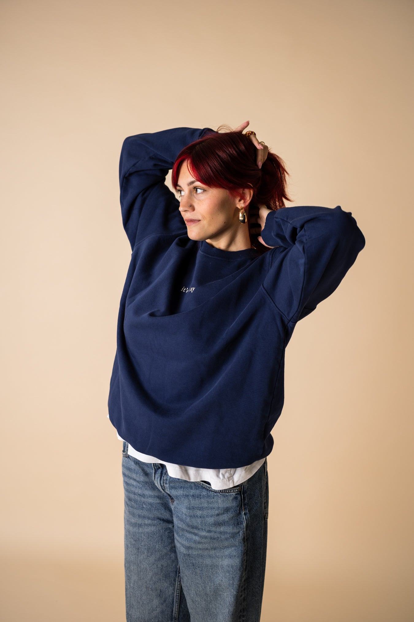 Woman wearing blue IT’S OKAY organic cotton crewneck, relaxed oversized fit with arms raised.