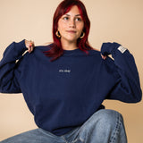 Woman wearing navy IT’S OKAY organic cotton crewneck, showing oversized fit while seated.