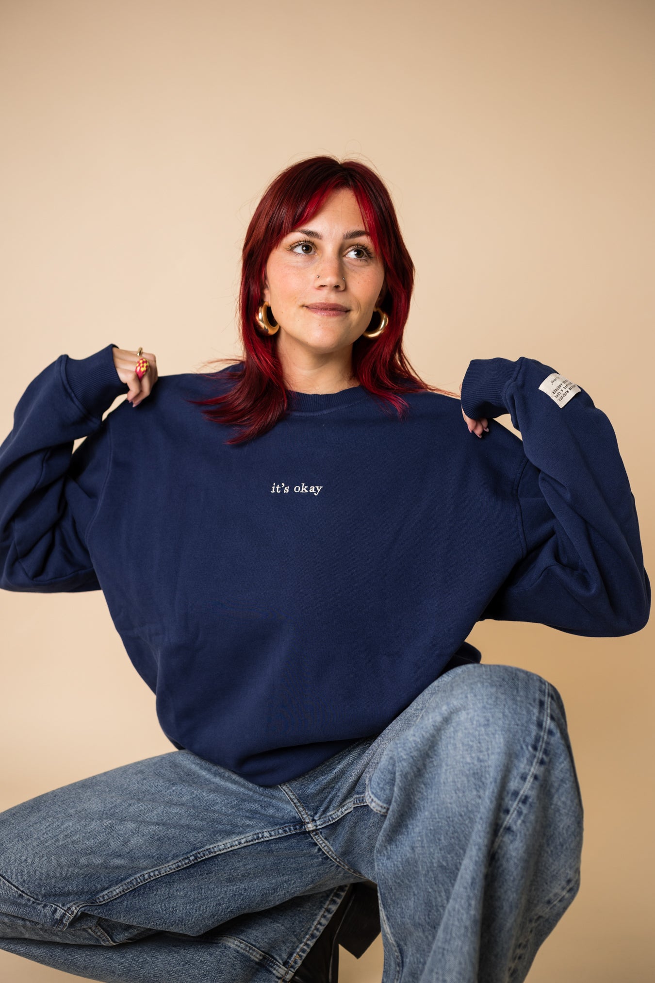 Woman wearing navy IT’S OKAY organic cotton crewneck, showing oversized fit while seated.