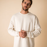 Blond man wearing an organic crew neck sweater in off-white, seamless design. Relaxed and minimal style, perfect for any occasion. Studio Photography gender neutral apparel