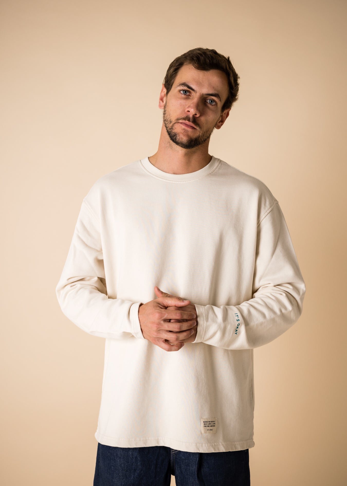 Blond man wearing an organic crew neck sweater in off-white, seamless design. Relaxed and minimal style, perfect for any occasion. Studio Photography gender neutral apparel