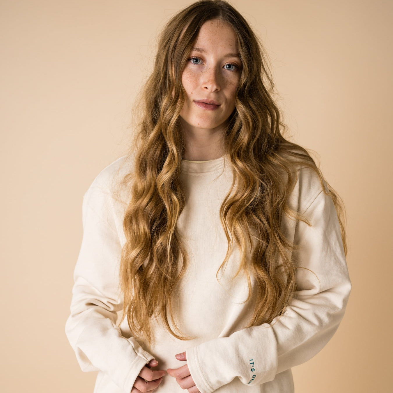 blond girl with blue eyes wearing an organic crew neck sweater in off-white, seamless design. Relaxed and minimal style, perfect for any occasion. Studio Photography gender neutral apparel