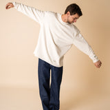 Blond man wearing an organic crew neck sweater in off-white, seamless design. Relaxed and minimal style, perfect for any occasion. Studio Photography gender neutral apparel