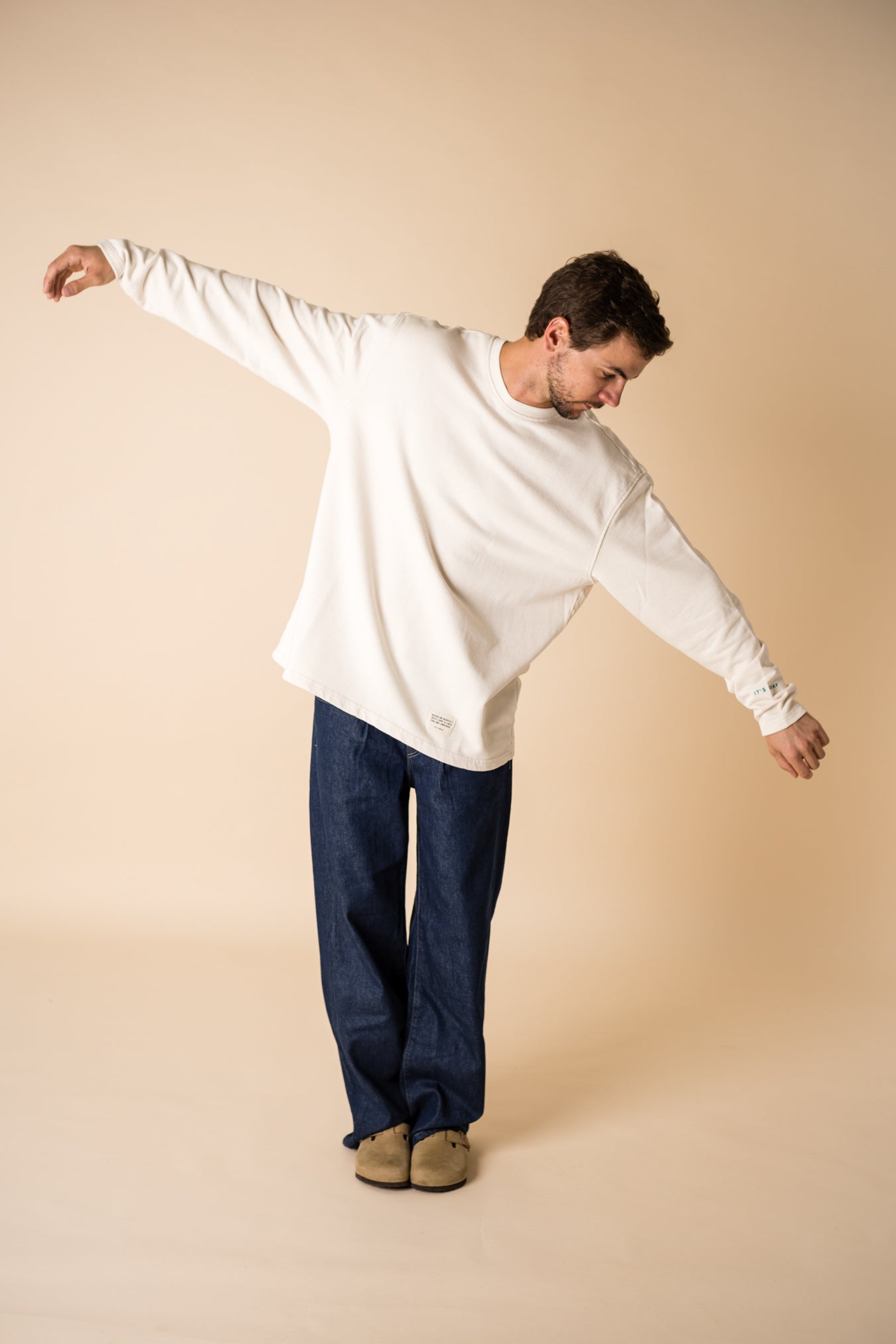 Blond man wearing an organic crew neck sweater in off-white, seamless design. Relaxed and minimal style, perfect for any occasion. Studio Photography gender neutral apparel