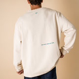 Man's back wearing an organic crew neck sweater in off-white, seamless design. Relaxed and minimal style, perfect for any occasion. You can read the embroidery: Cultivate what matters Studio Photography gender neutral apparel.