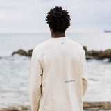 Model José wearing Cultivate Crew at the beach. Photo of the back of the crewneck: cultivate what matters