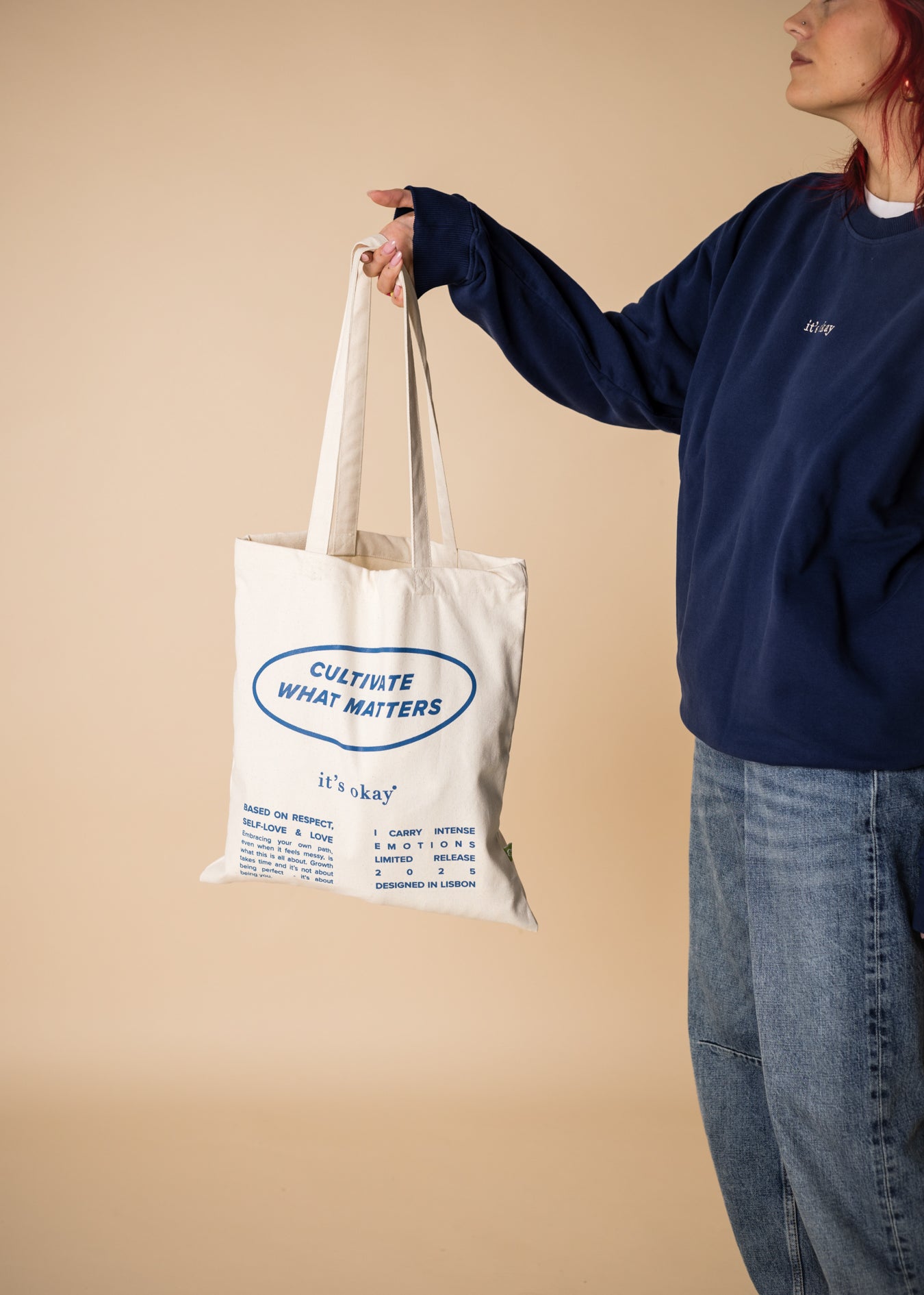 organic tote bag cultivate what matters, screenprinting, white and blue. Girl witrh crew blue pick up the tote bag.